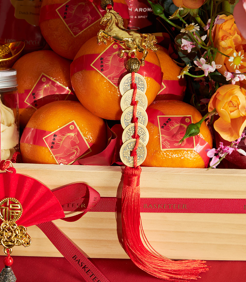 Luxury Chinese New Year gift basket with mandarin oranges, gold horse charm, red tassel, and festive florals in wooden crate