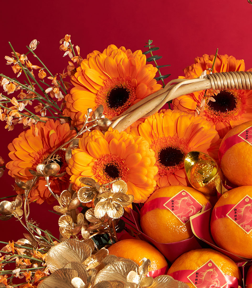 Vibrant Chinese New Year mandarin orange gift basket with golden floral accents and gerbera daisies