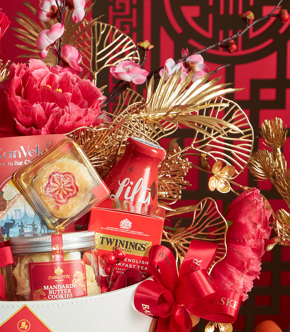 Red festive gift basket with gourmet tea, mandarin butter cookies, and Chinese New Year treats accented with peonies and