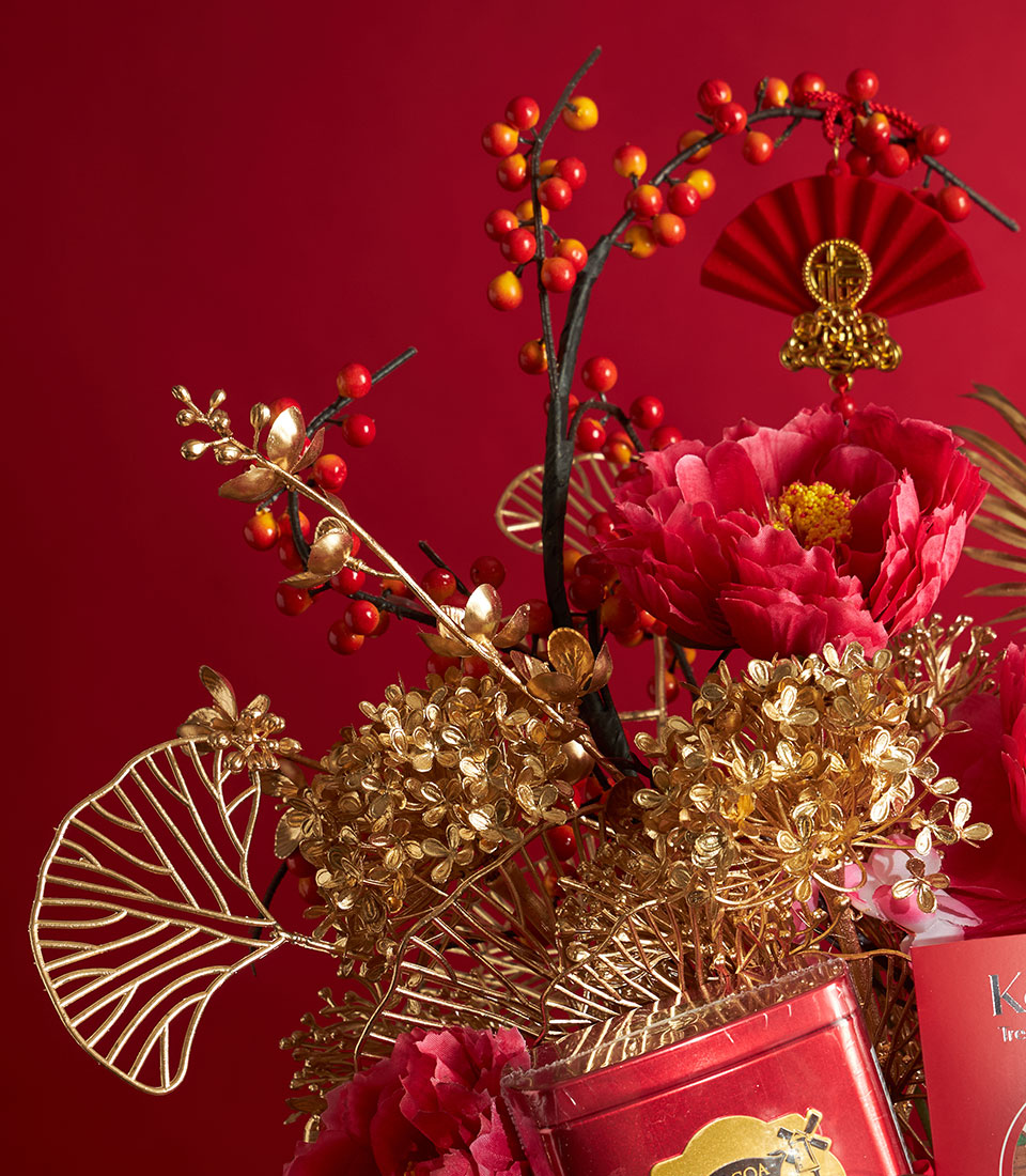 Festive red and gold Chinese New Year gourmet gift basket with artificial peonies, golden flowers, and celebratory ornaments