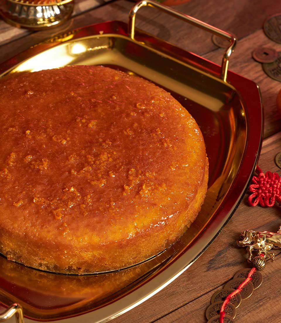 Golden mandarin sponge cake with glossy glaze on gold tray, Chinese New Year gift with auspicious décor