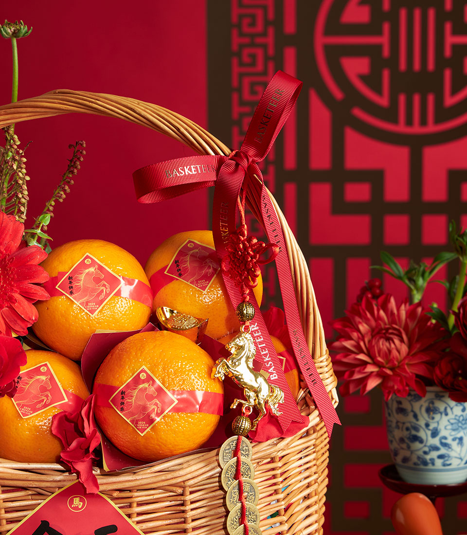Festive red and gold mandarin orange basket with fresh red flowers and traditional Chinese New Year charms