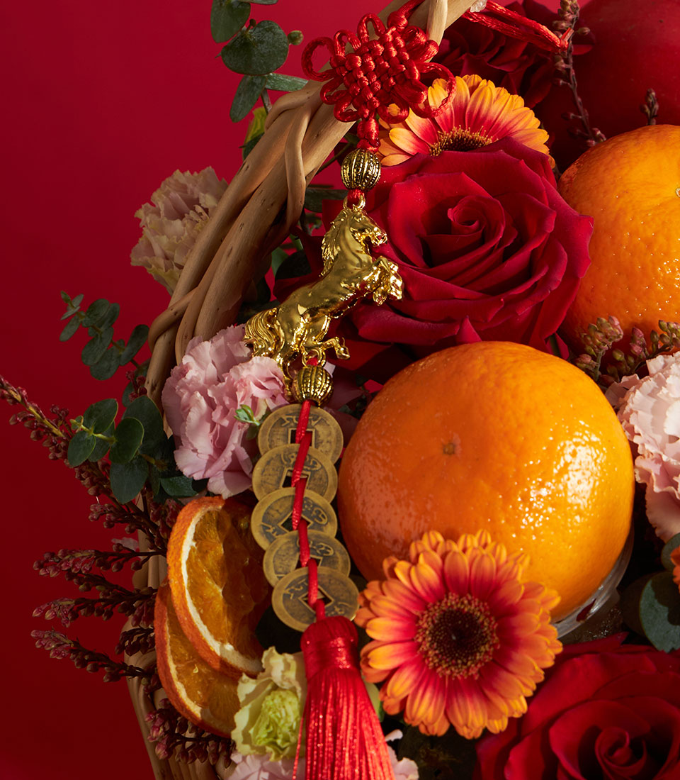 Festive Chinese New Year fruit and flower basket with fresh roses, carnations, gerberas, oranges, and gold horse charm on