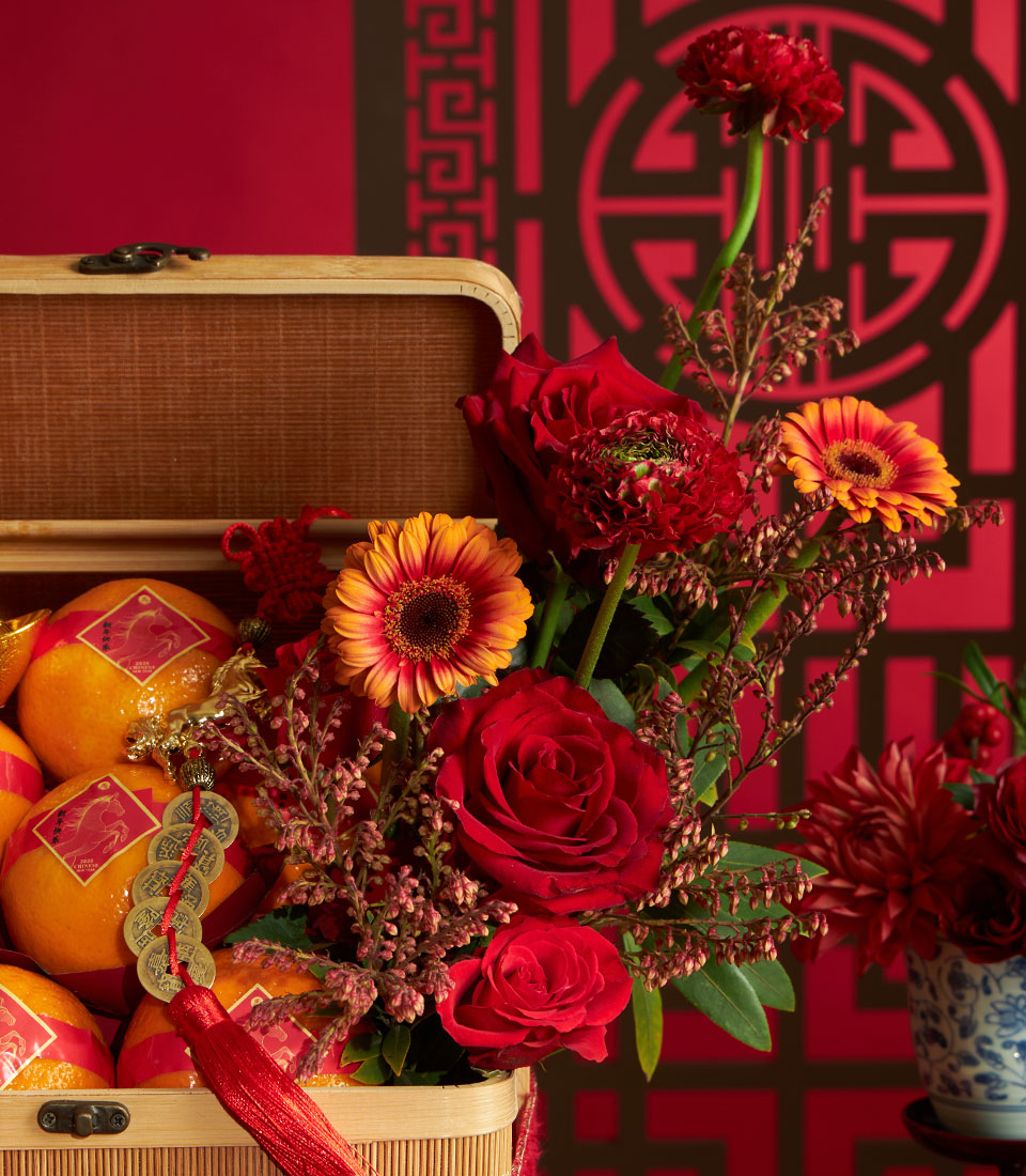 Festive Chinese New Year mandarin orange basket with red roses and gerbera daisies, lucky coins charm, and golden horse