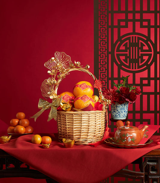 Festive Chinese New Year mandarin orange gift basket with gold accents, red tassel bow, and ceremonial ornaments on red