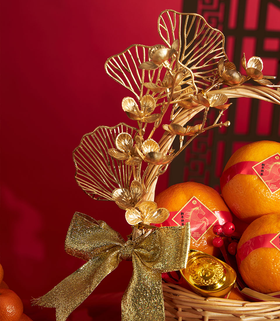 Woven wicker basket with mandarin oranges, red ribbons, gold bow, and symbolic gold ingot for Chinese New Year gifting