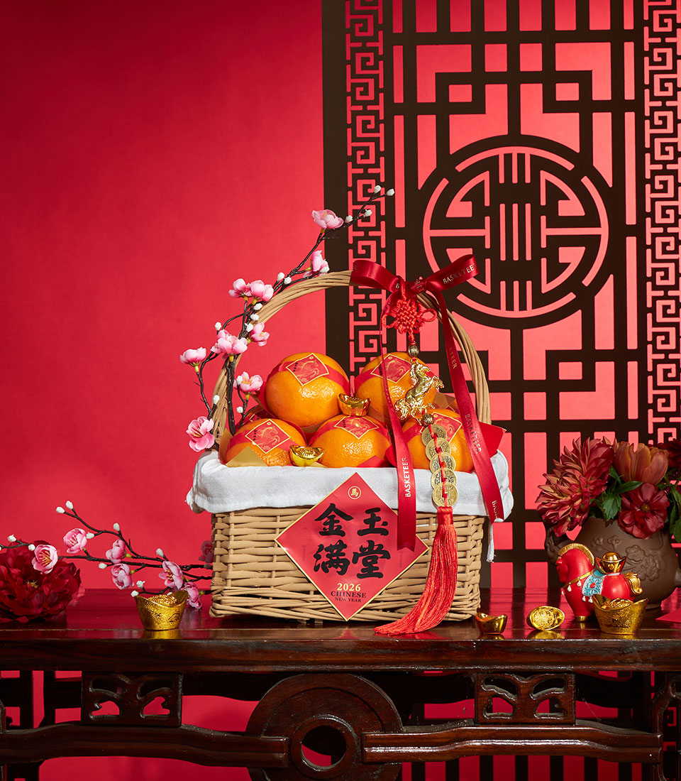 Premium mandarin prosperity basket with red ribbons, gold charms, and festive Chinese New Year decorations on woven wicker