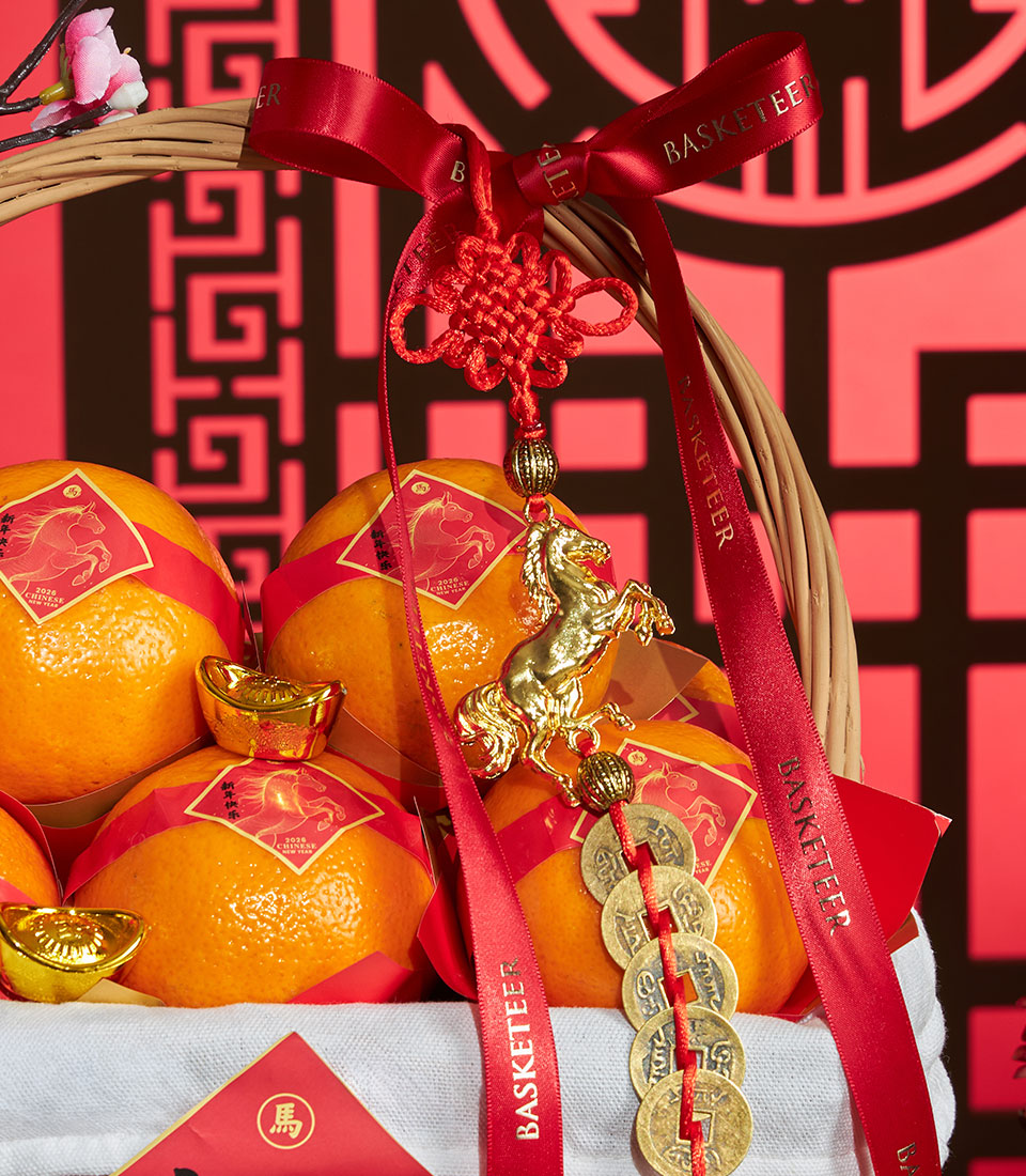 Mandarin oranges gift basket with red ribbons, golden horse charms, and Chinese coins for Chinese New Year prosperity