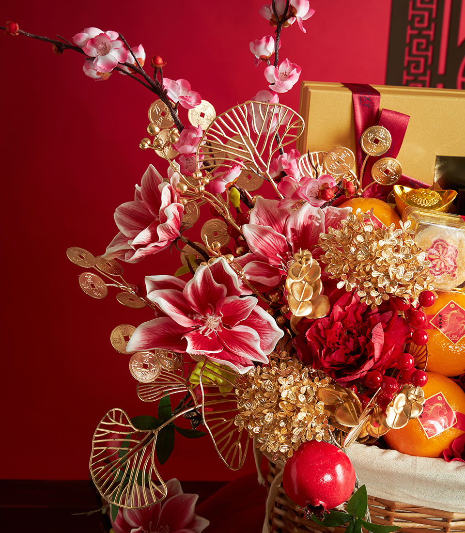 Red and gold Chinese New Year gift basket with fresh mandarin oranges, pomegranate, and gourmet selections