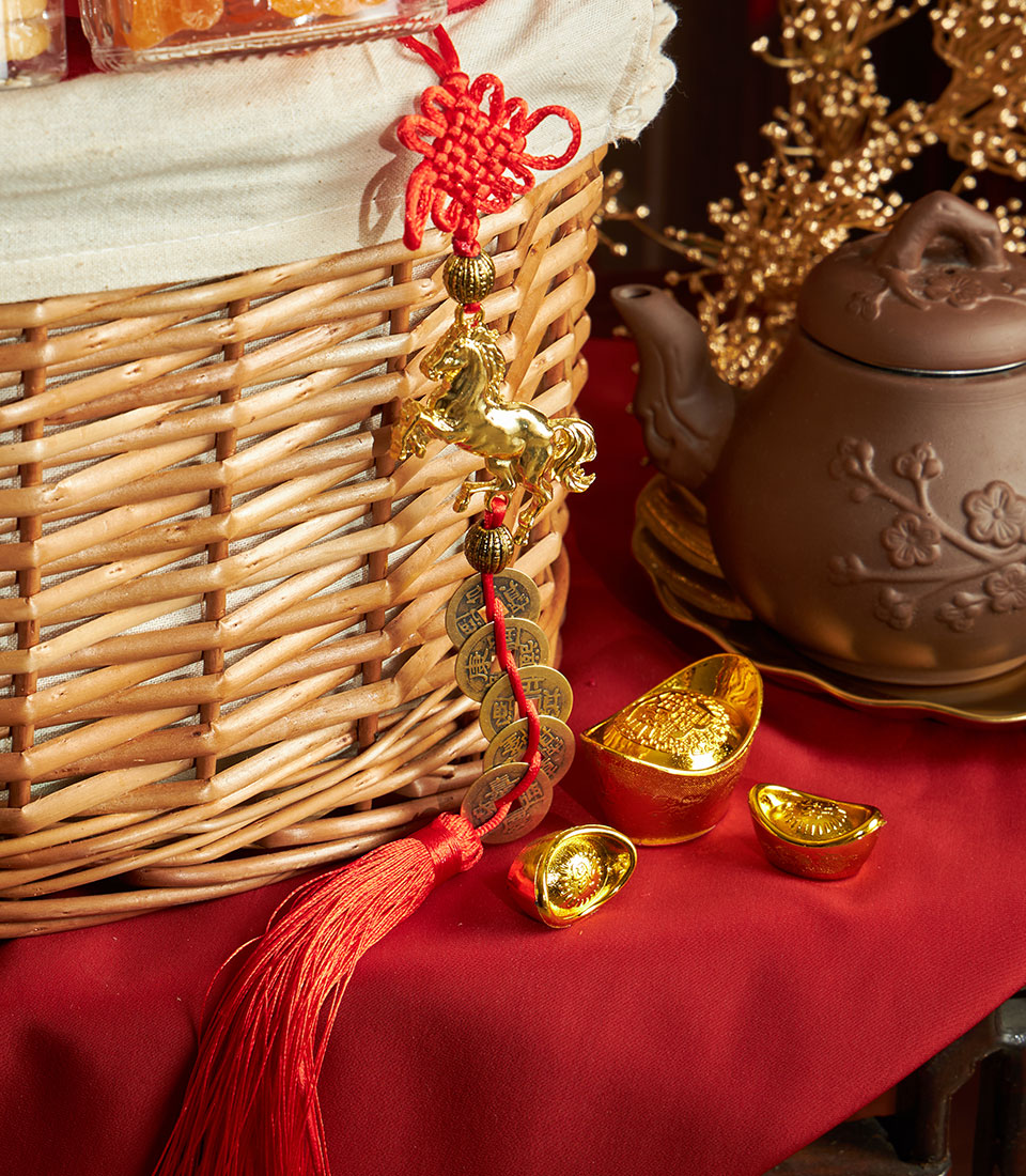Luxury Chinese New Year gift basket with mandarin oranges, ceramic teapot, golden ingots, and traditional charms on red