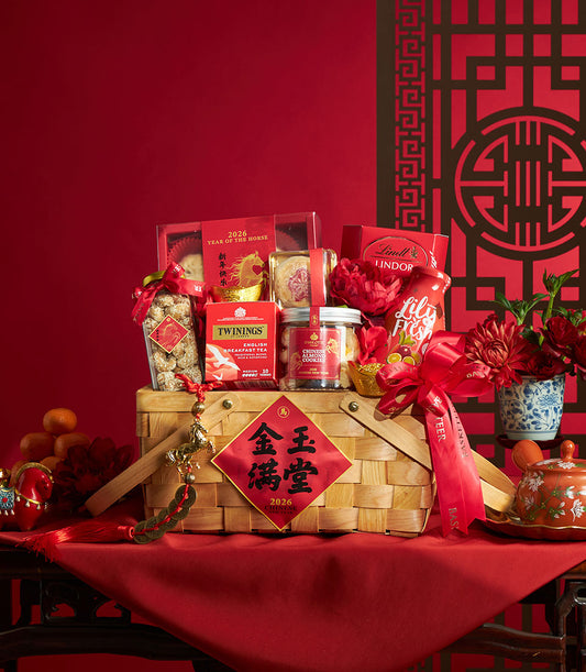 Woven gift basket filled with premium treats, tea, and gourmet goods, decorated with red peonies and gold accents for