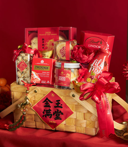 Chinese New Year gourmet gift basket with red ribbon, luxury chocolates, artisan cookies, and gold charm on woven wood