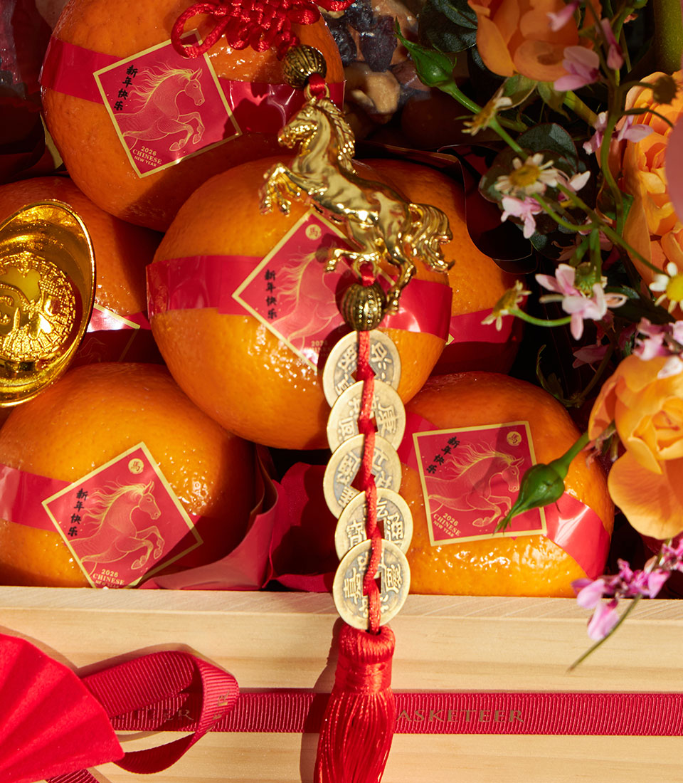 Luxury mandarin orange gift basket with red ribbons, golden horse charm, and festive Chinese New Year decorations in wooden