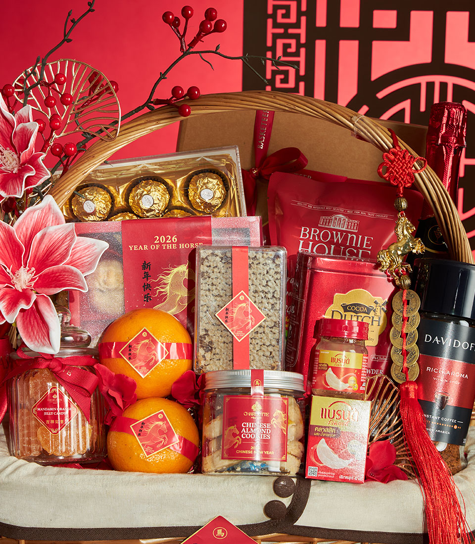 Premium Chinese New Year gift basket with red and gold chocolates, coffee, cookies, and fresh oranges in woven wicker