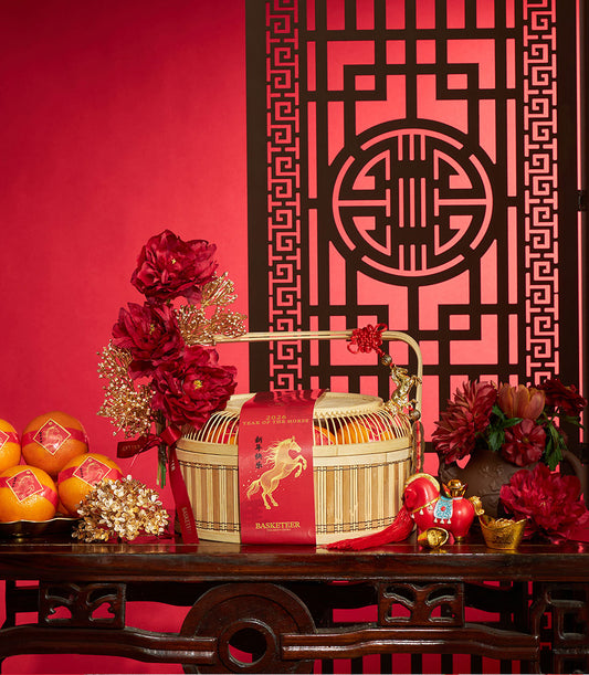 Bamboo basket of mandarin oranges with red ribbon, red peonies, and golden horse figurine for Chinese New Year