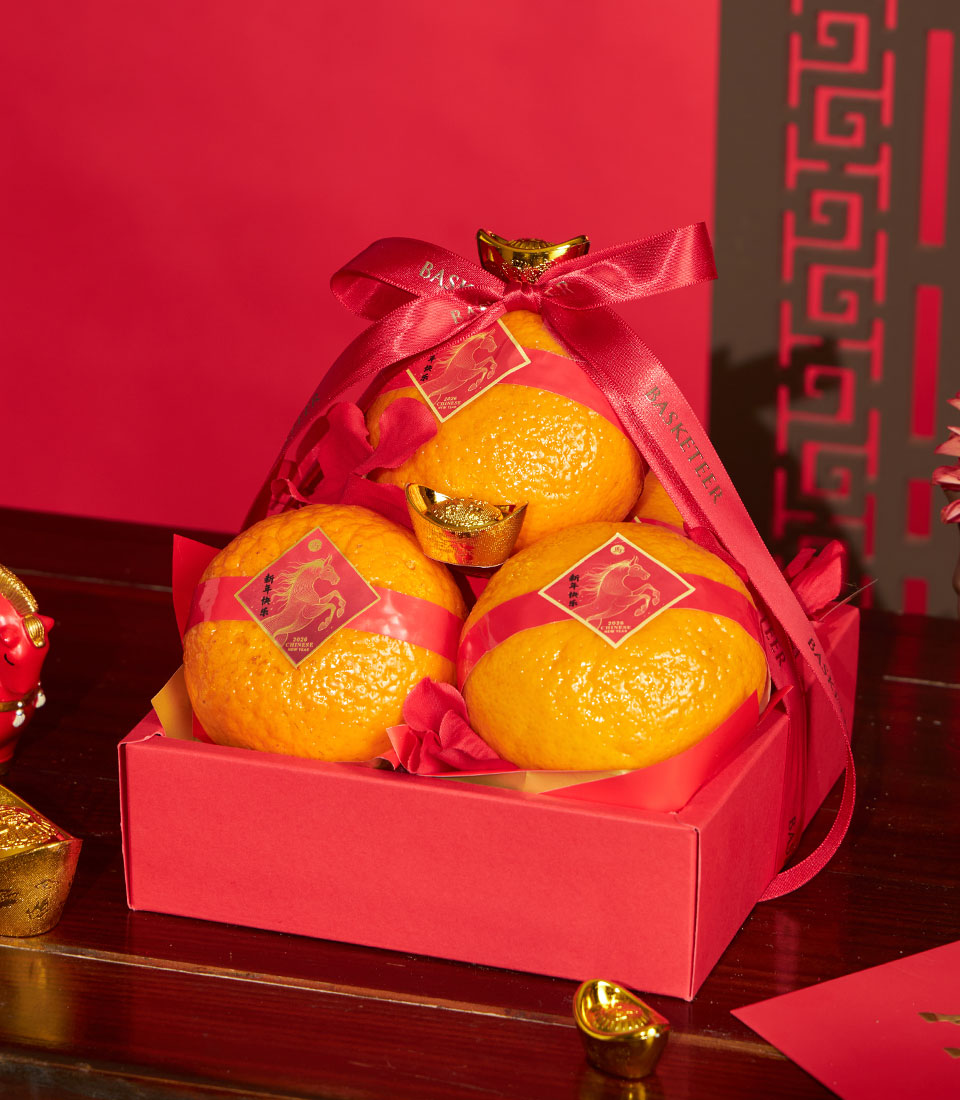 Mandarin oranges with red silk ribbons and gold accents in premium gift box for Chinese New Year