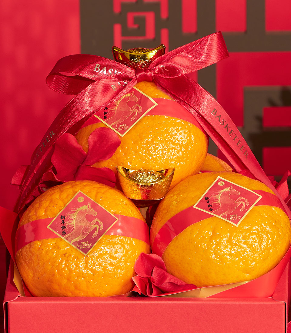 Festive mandarin orange gift box with golden horse lucky charms and red satin ribbons for Chinese New Year