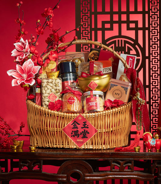 Woven wicker Chinese New Year gift basket with gourmet snacks, golden ingots, and festive red ribbons on red patterned