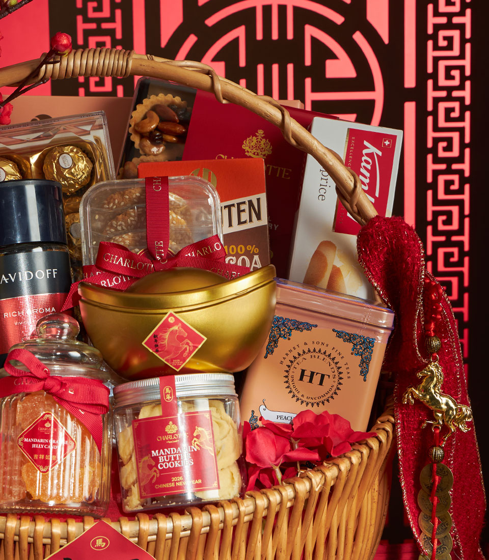 Woven wicker basket filled with Mandarin butter cookies, jars of treats, golden ingot containers, and fine teas with red