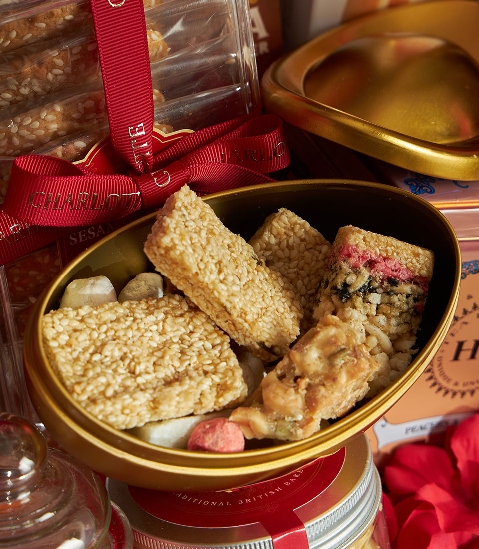 Prosperity Gourmet Chinese New Year gift basket with sesame bars, nougat, and artisan sweets in gold tin and ribbon-tied box