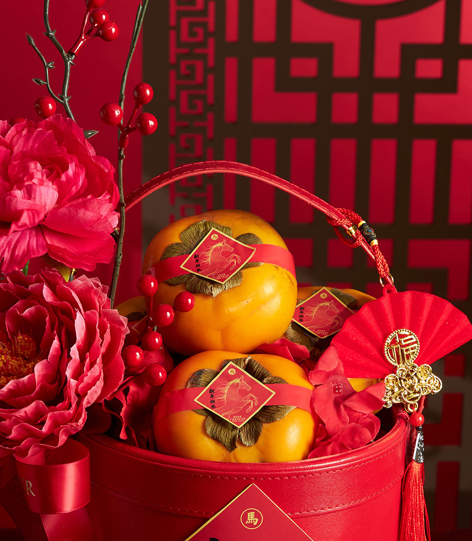 Red Chinese New Year persimmon gift basket with artificial peonies, berries, and lucky fan charm