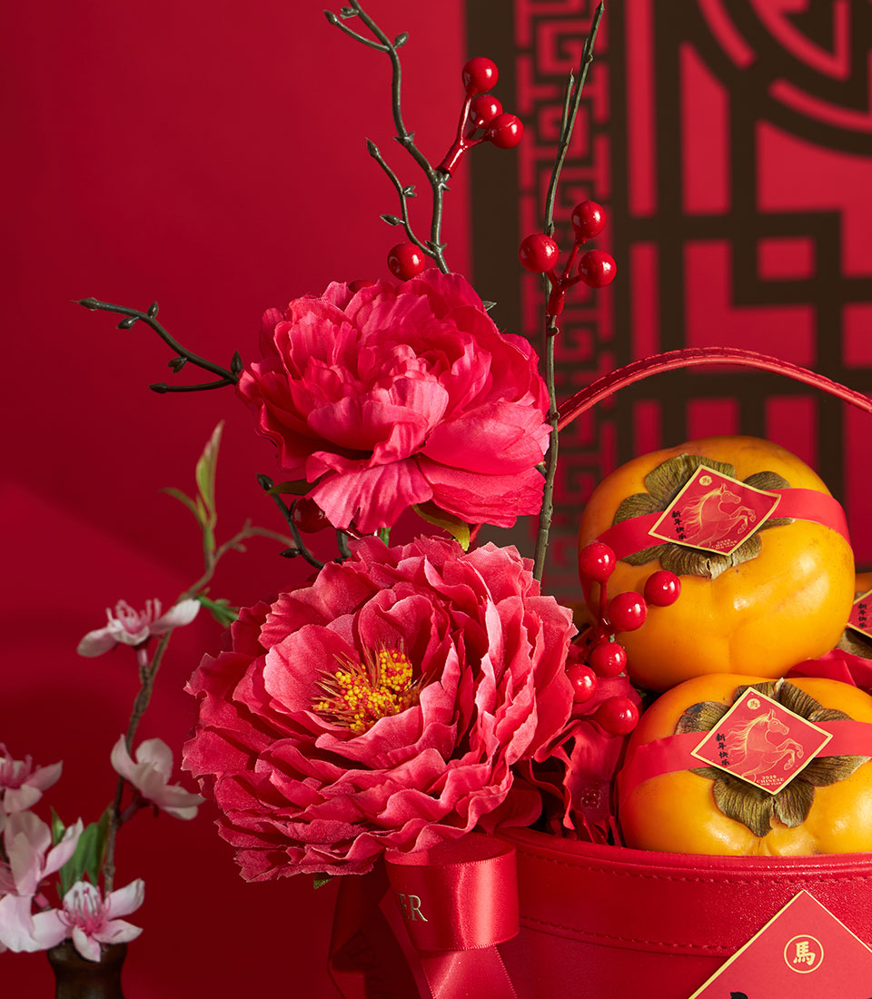 Luxury red gift basket with artificial pink peonies, burgundy branches, yellow persimmons and golden horse charm tags for