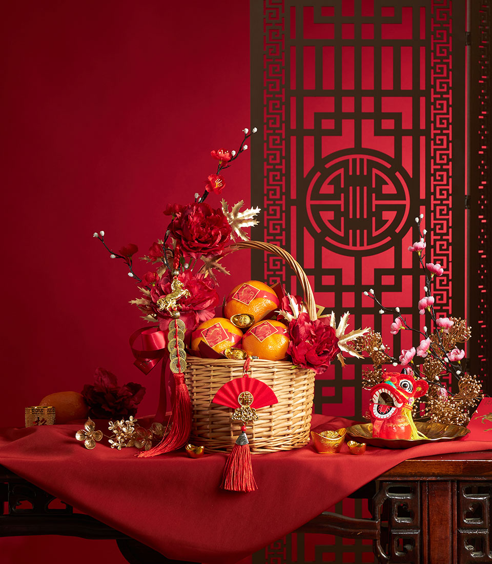 Luxury mandarin orange wicker basket with red and gold accents, red peonies, and lucky coins tassel for Chinese New Year