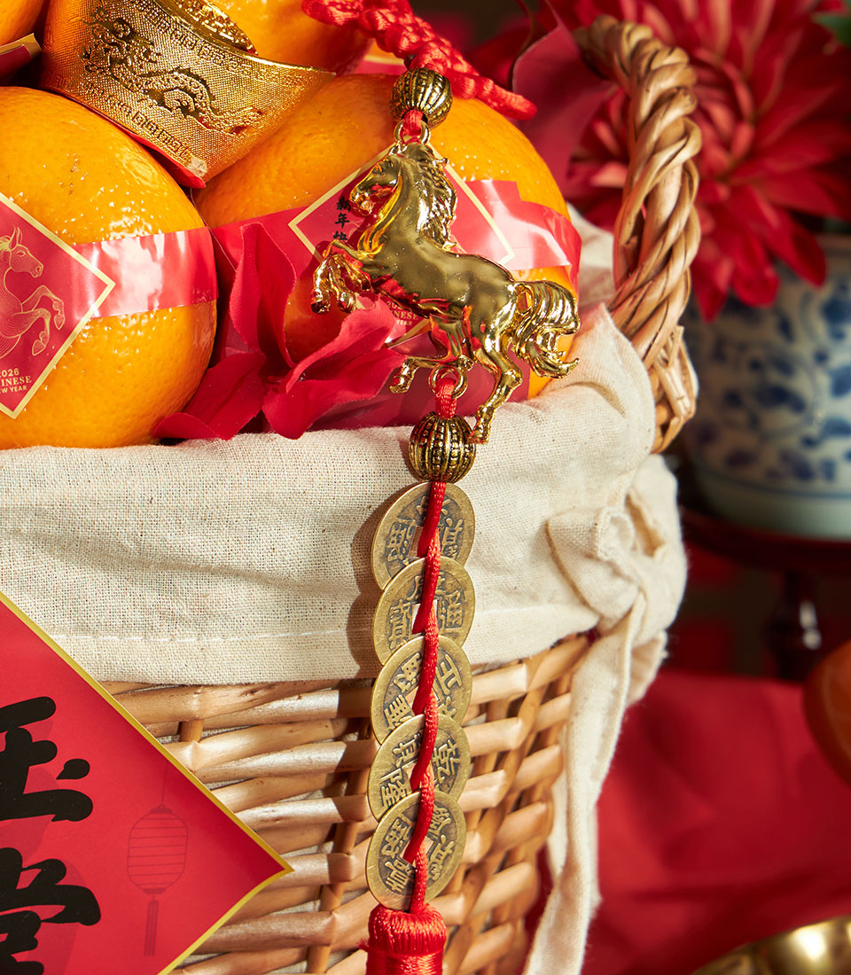 Woven wicker basket with mandarin oranges, red paper bands, gold ingot, and lucky coin tassel for Chinese New Year