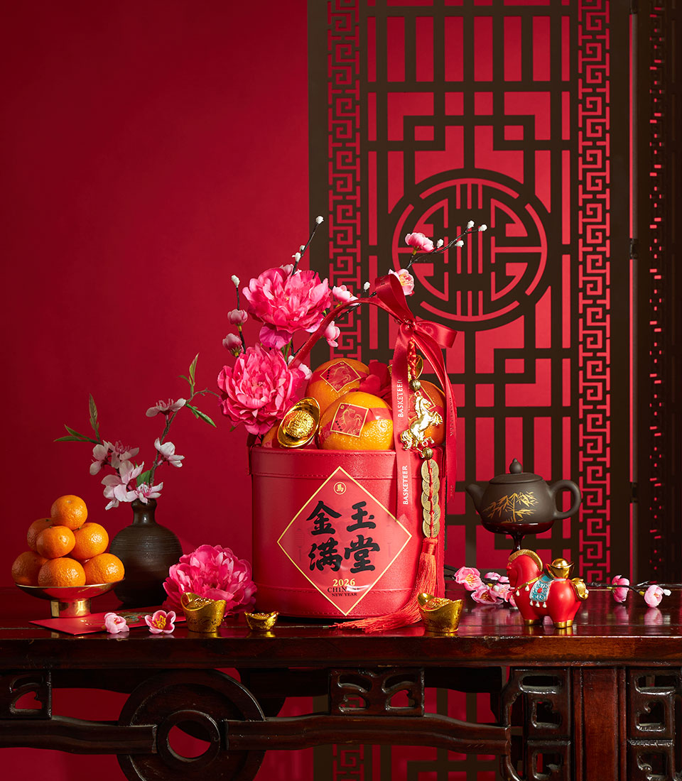 Red Chinese New Year gift box with mandarin oranges, gold ingots, and pink peonies, surrounded by festive florals and