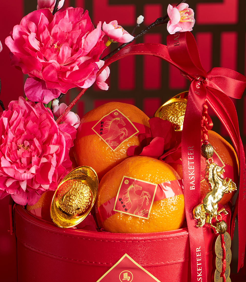 Festive Chinese New Year mandarin orange gift basket with red satin bow, artificial peonies, and gold coin charms