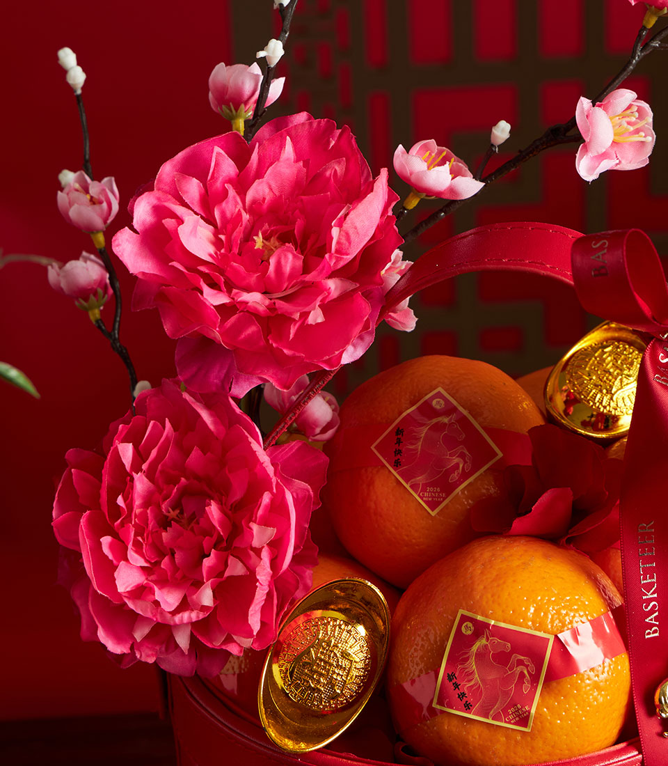Vibrant red Chinese New Year mandarin orange basket with gold ingots, artificial pink flowers, and lucky horse label accents