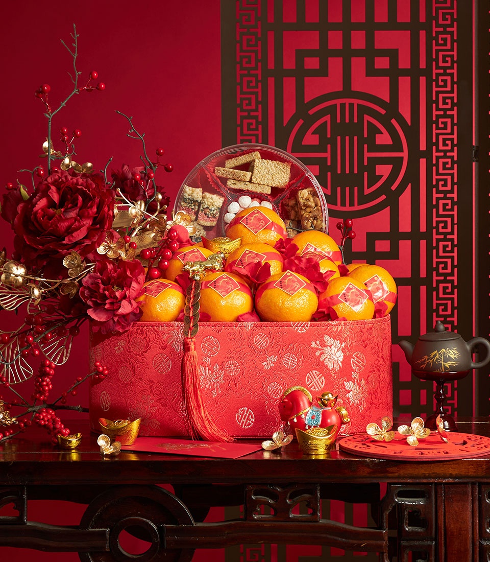 Festive red gift box with mandarins, snacks, and deep red peonies for Chinese New Year celebration
