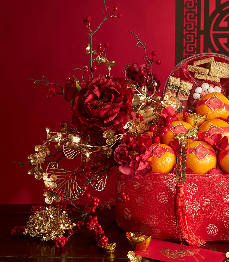 Luxury Chinese New Year gift basket with red peonies, fresh mandarins, gold accents, and prosperity symbols
