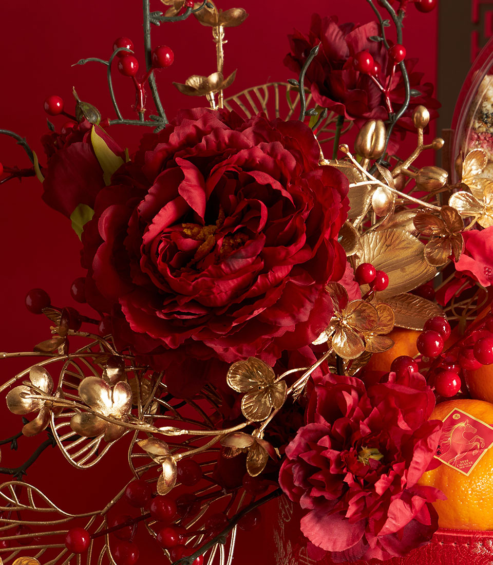 Festive Chinese New Year mandarin and persimmon gift basket with red peonies, golden leaves, and fresh citrus fruits against