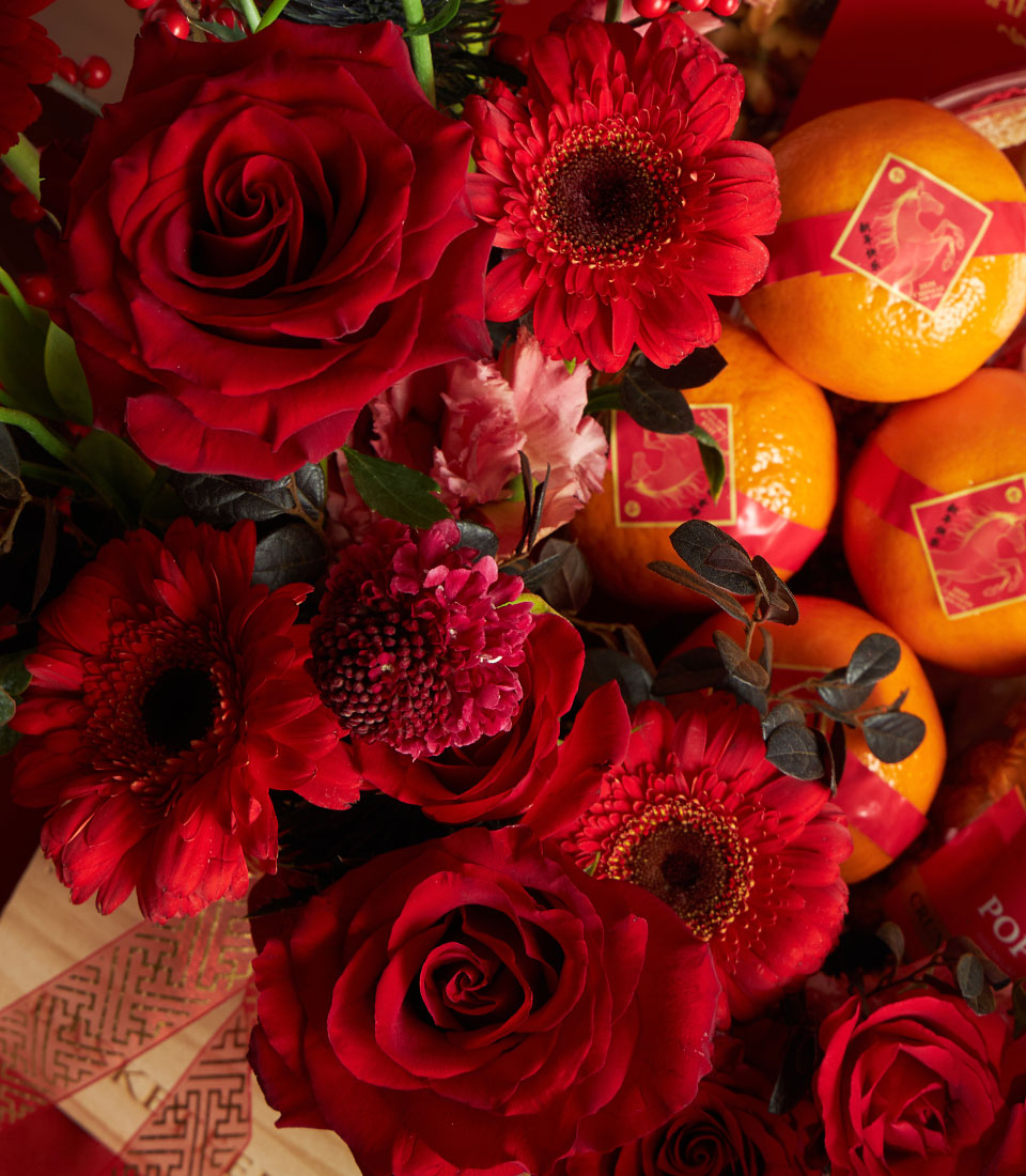 Luxury red roses, gerbera daisies, and fresh mandarins with gold horse bands in premium Chinese New Year gift basket