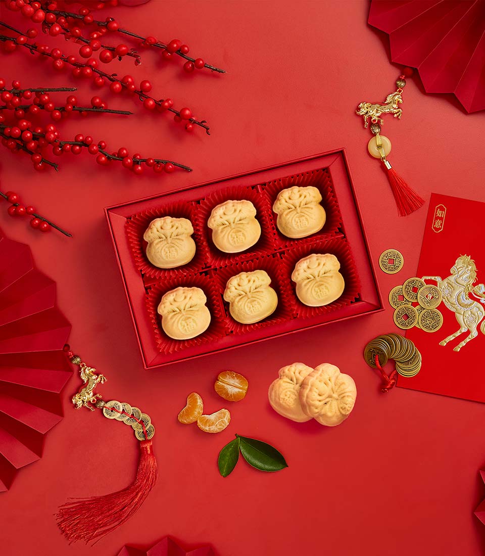 Prosperity pastry gift box with six artisan pastries, red envelope, gold charms, and mandarin oranges for Chinese New Year