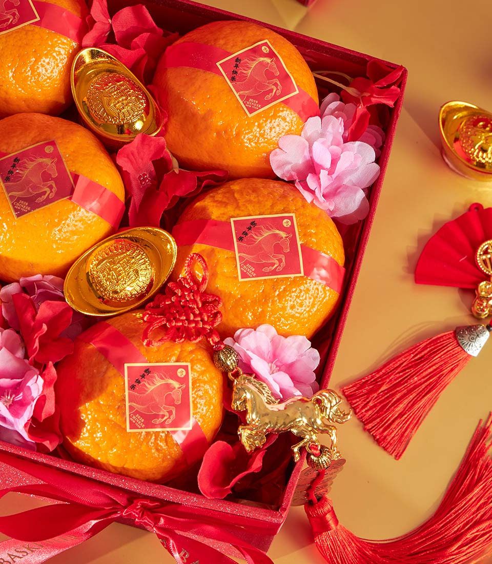 Luxury red gift box with fresh mandarin oranges, golden ingots, and Chinese New Year decorations