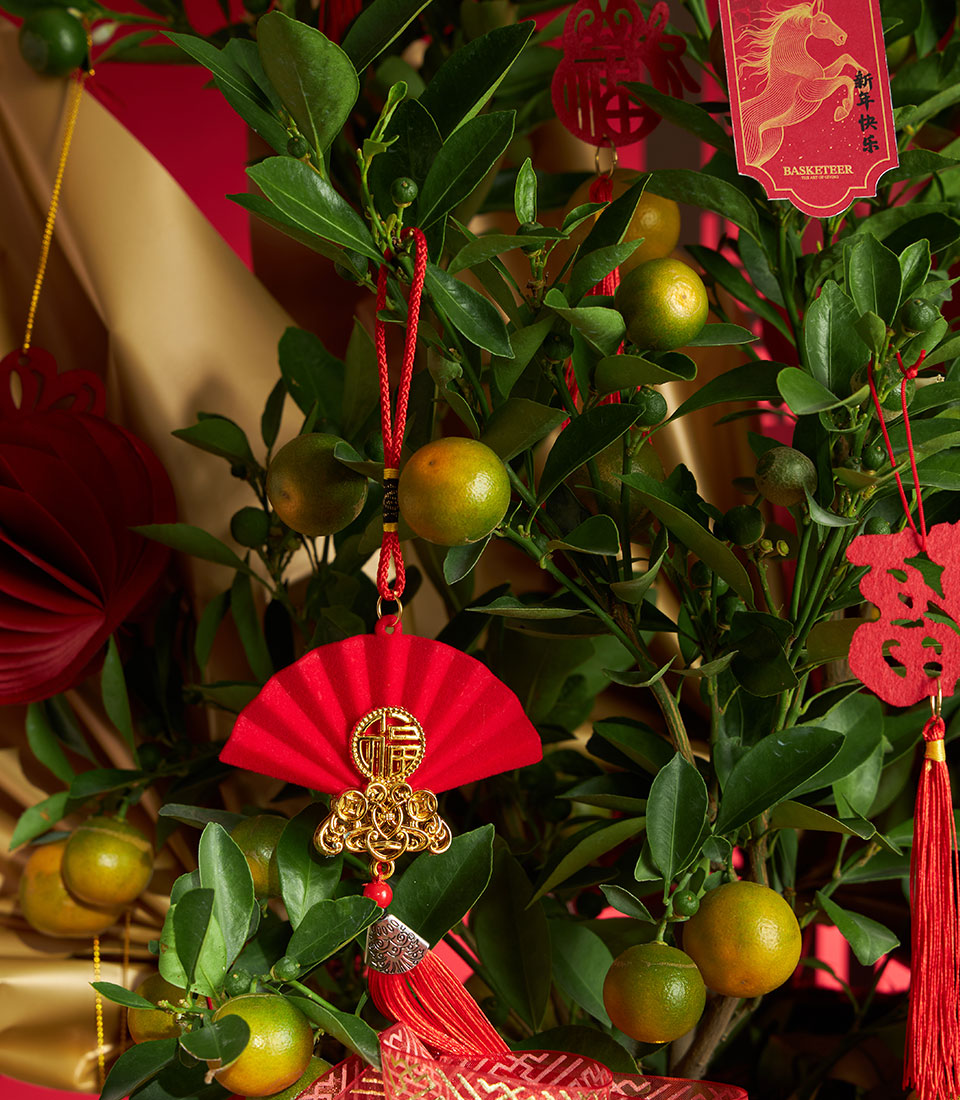 Kumquat tree with red and gold Chinese New Year decorations, lucky fruit gift for celebrations