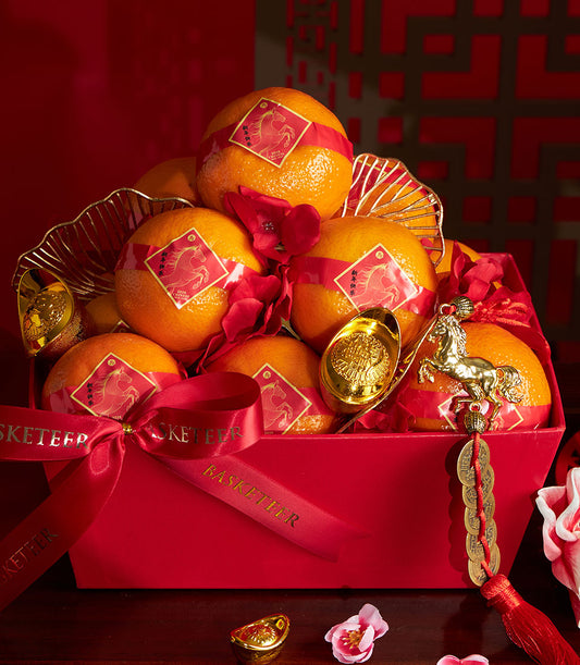 Mandarin orange gift basket with red ribbon wrapping, golden horse charms, and festive Chinese New Year decorations in