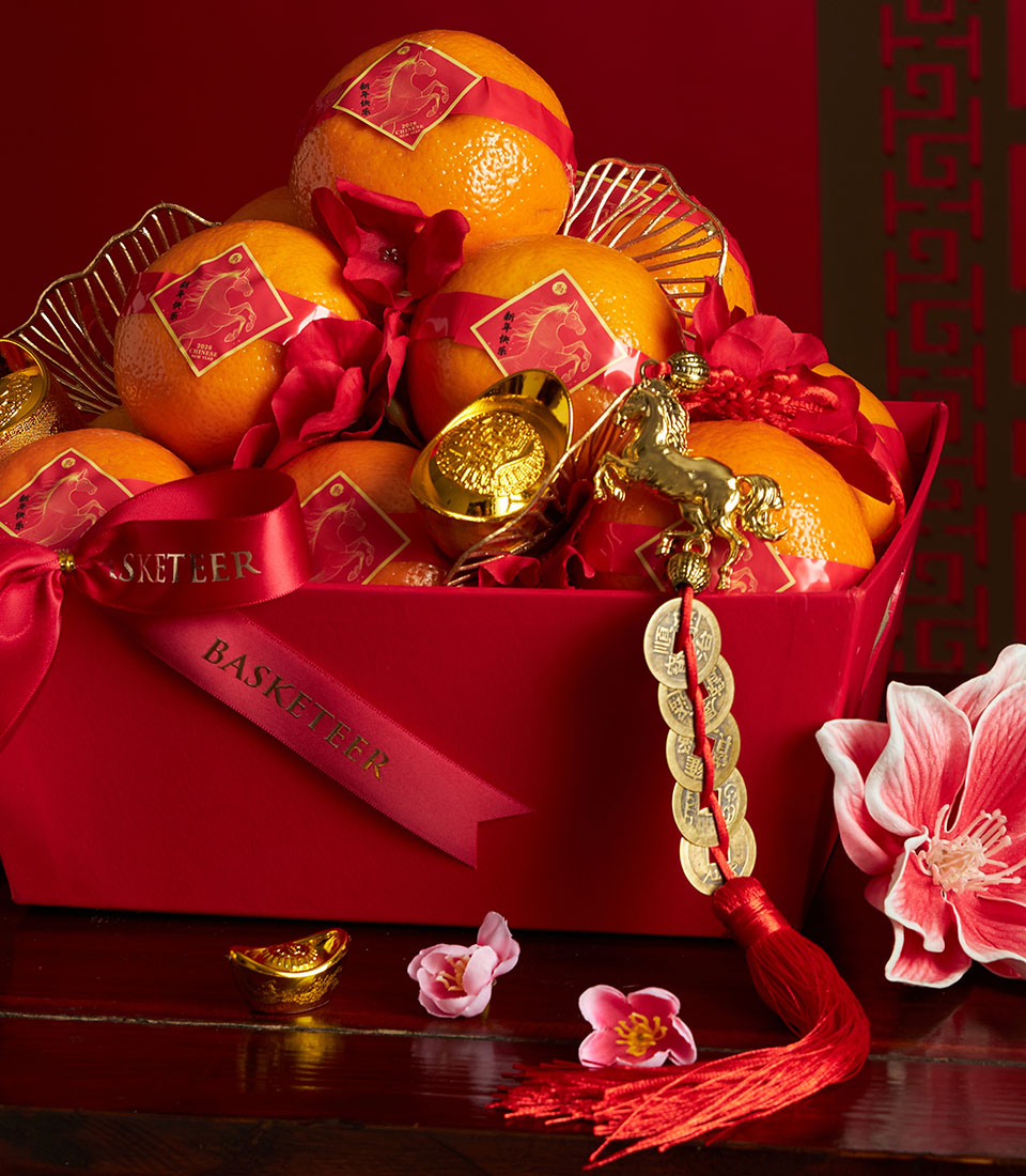Mandarin orange Chinese New Year gift basket with red paper bands, golden horse charms, and lucky coins in red satin-tied box