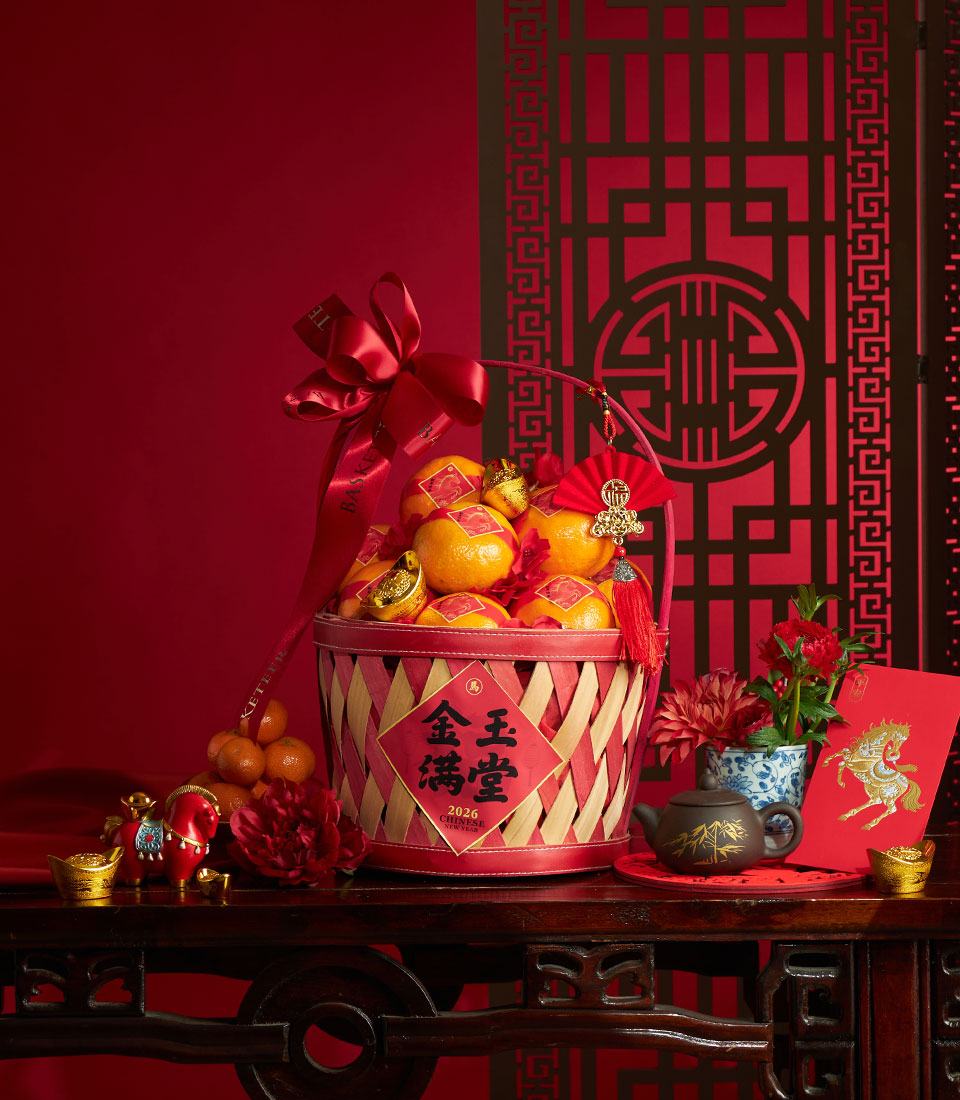 Festive red and natural bamboo basket filled with bright mandarins, gold ingots, and lucky symbols for Chinese New Year