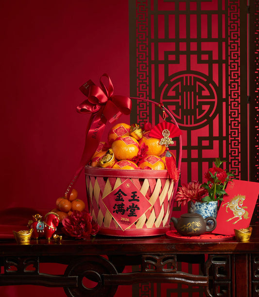 Festive red and natural bamboo basket filled with bright mandarins, gold ingots, and lucky symbols for Chinese New Year