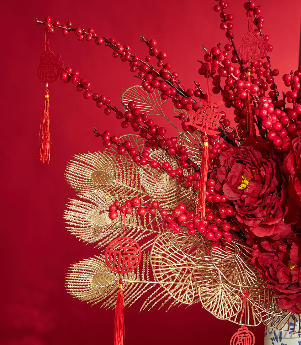 Vibrant red peony artificial flower arrangement with gold peacock feathers and Chinese New Year tassels in porcelain vase