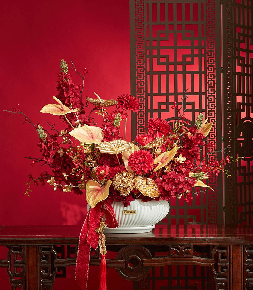 Basketeer premium hamper delivery Thailand: Red and gold artificial flowers in decorative vase, with festive red ribbon. Perfect corporate gift Bangkok.
