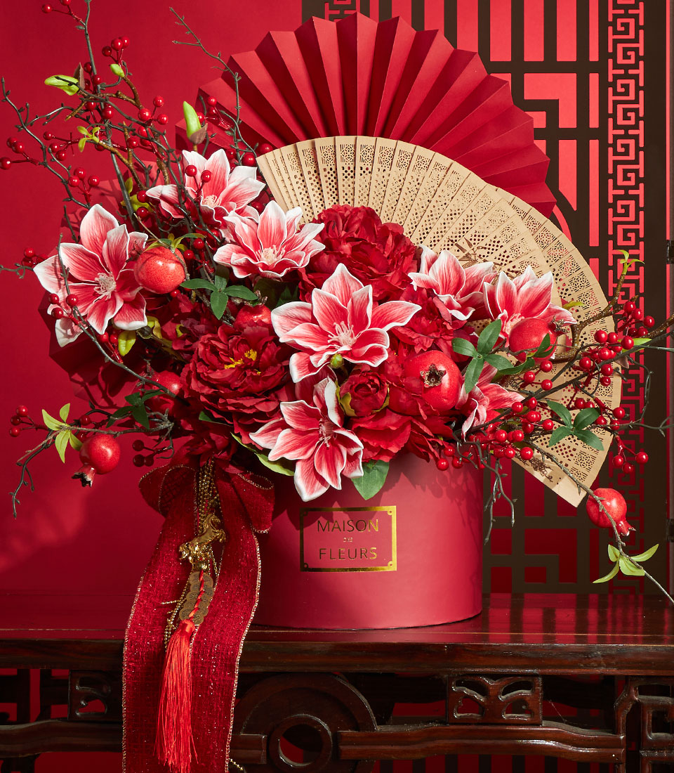 Basketeer's luxury gift for Chinese New Year: red floral arrangement with lilies and pomegranates, plus a bamboo fan in a festive red gift box. Perfect corporate gift Bangkok.