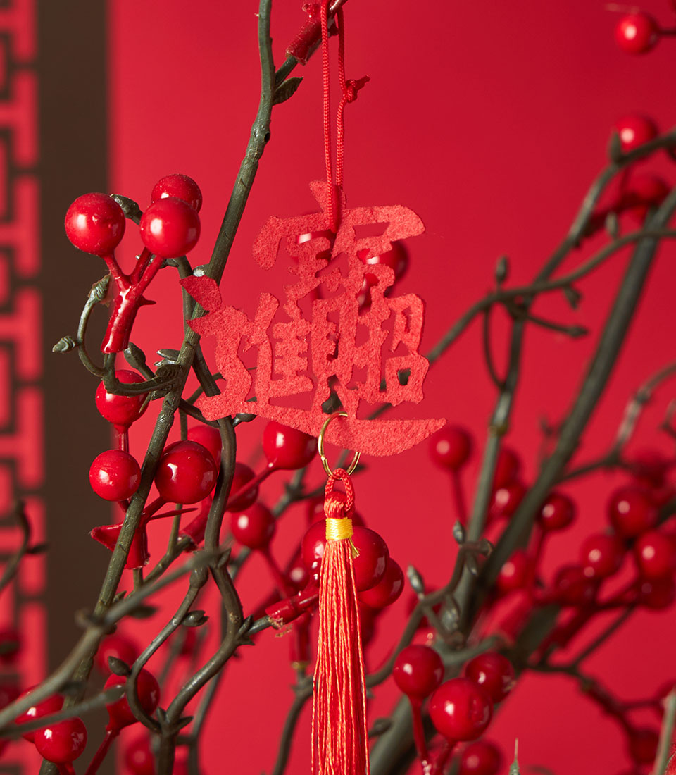Red berry branch with gold-accented Chinese New Year felt ornament and tassel, lucky prosperity decoration