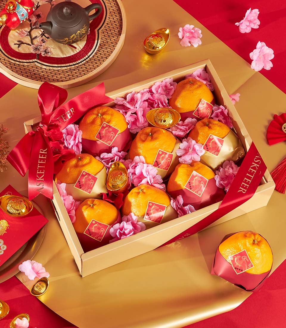 Dekopon orange gift box with tangerines, red rooster wrapping, pink flowers, and gold prosperity charms on red and gold