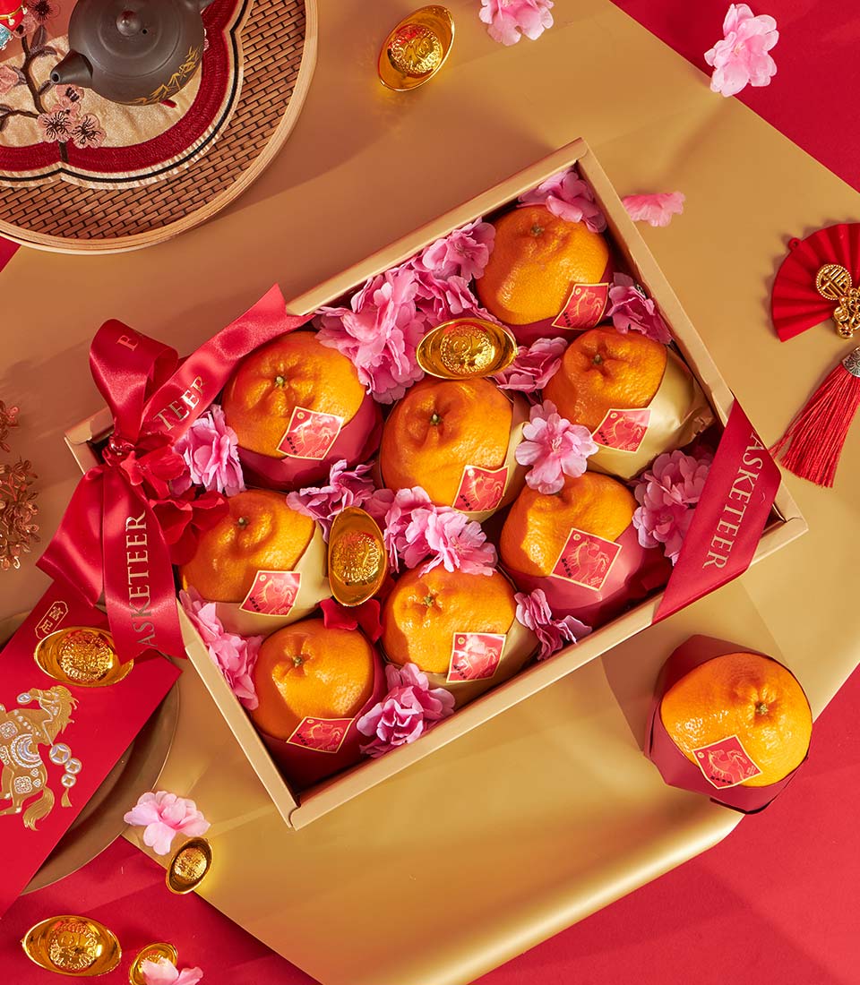 Premium golden tangerine gift box with pink florals, red and gold wrapping, and prosperity symbols for festive gifting