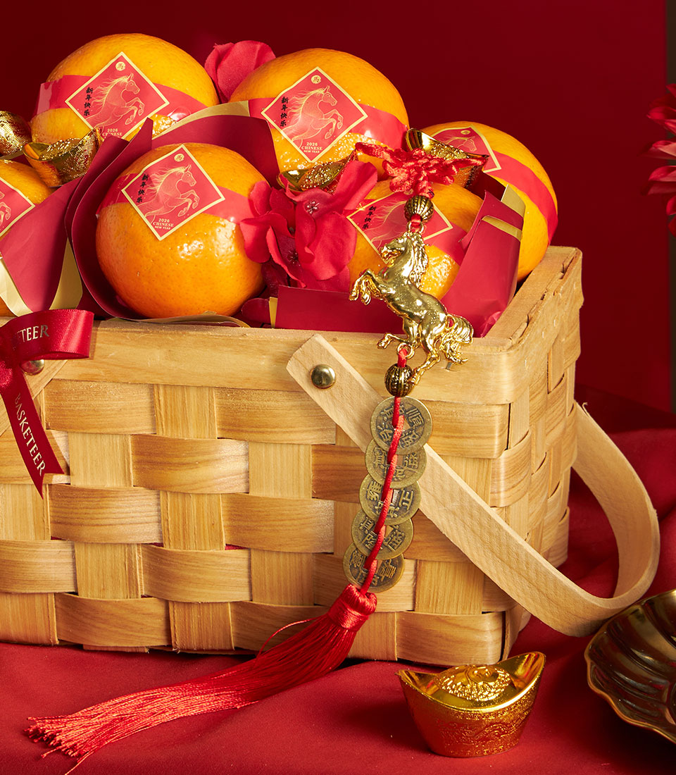 Woven wicker basket filled with mandarin oranges and red festive accents for Chinese New Year gifting