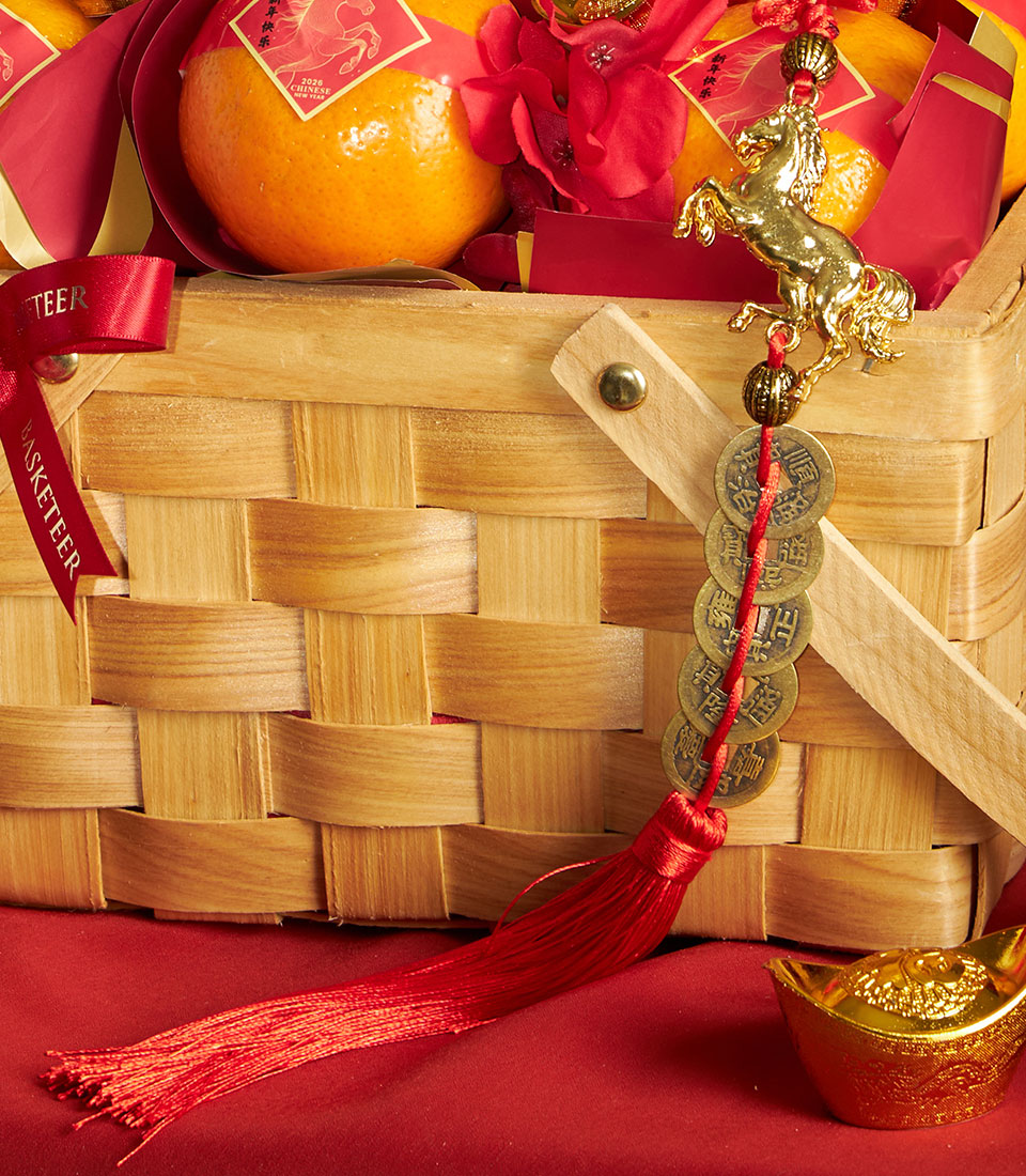 Basketeer's luxury Chinese New Year gift hamper: Mandarin oranges in a classic wooden basket, adorned with a gold horse charm and red ribbon.